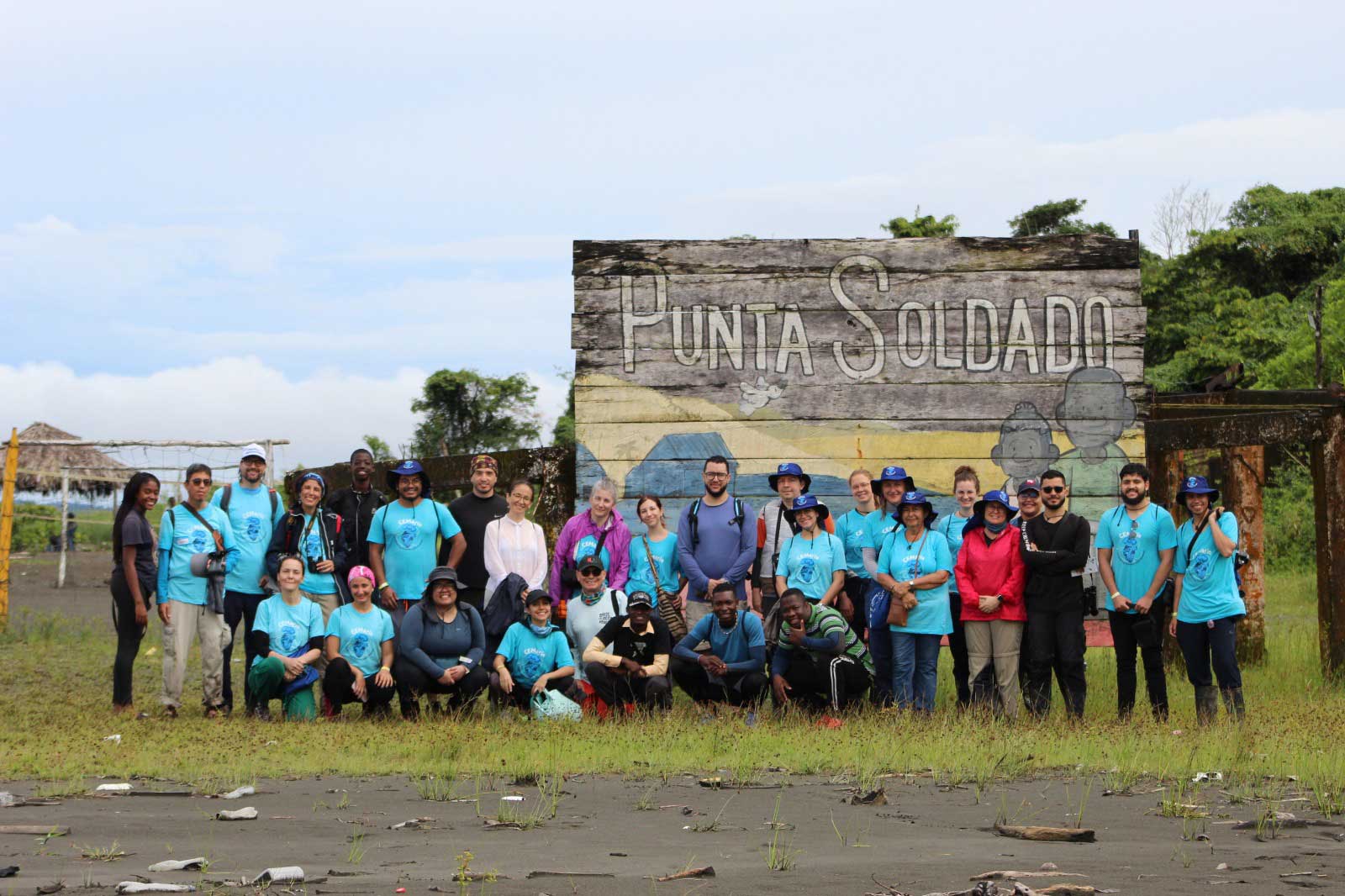 A group of people in front of a big sign with the words Punta Soldado