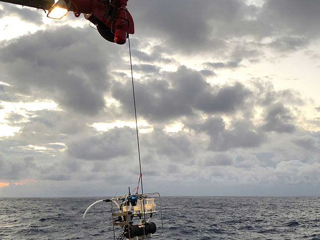 Ein Kran auf einem Schiff lässt eine Unterwasserroboter zu Wasser.