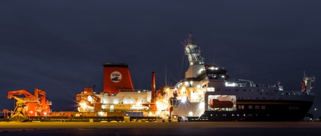 Ein großes beleuchtetes Schiff liegt in einem Hafen