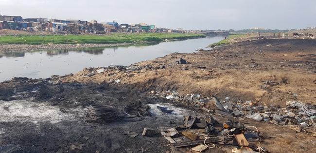 Electronic waste dump in  Agbogbloshie, shacks are seen in the background