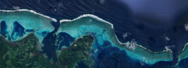 Aerial view of a coastal line in the tropics with offshore coral reefs