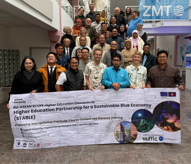 Eine Gruppe von Personen steht auf einer Treppe in einem modernen Gebäude. Vor der Gruppe halten einige Teilnehmende ein Banner mit der Aufschrift: „EU-ASEAN SCOPE Higher Education Connectivity – Higher Education Partnership for a Sustainable Blue Economy (STABLE) – Improving and Updating Curricula, Course Content and Advance Training“. Die Veranstaltung findet vom 18. bis 22. November 2025 am Leibniz-Zentrum für Marine Tropenforschung (ZMT) in Bremen statt.